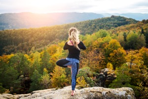Woman doing yoga pose on a mountain
