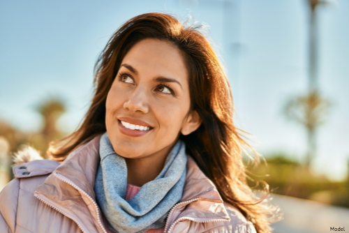 Woman outdoors in a winter coat smiling and pondering